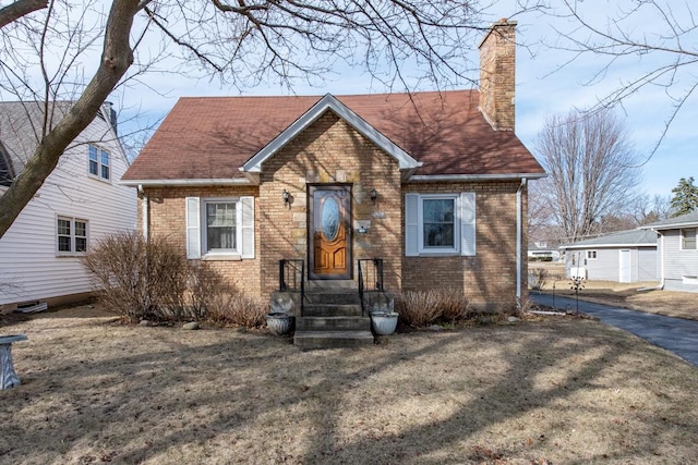 view of front of home featuring brick siding, a chimney, and a shingled roof