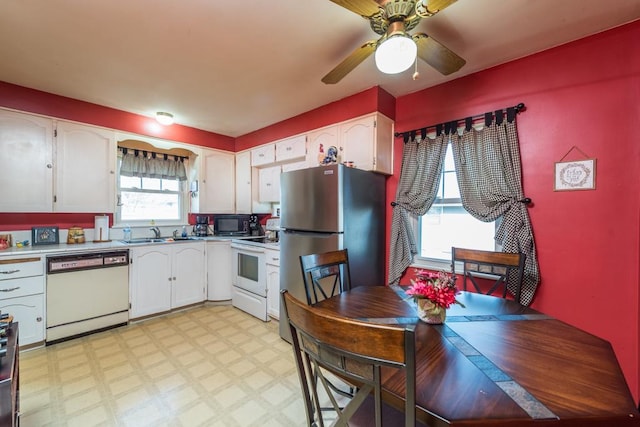 kitchen featuring light floors, light countertops, white appliances, white cabinetry, and a sink