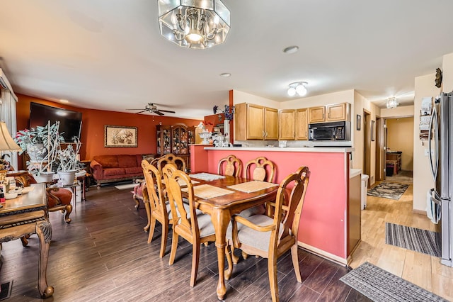 dining room featuring ceiling fan with notable chandelier and wood finished floors