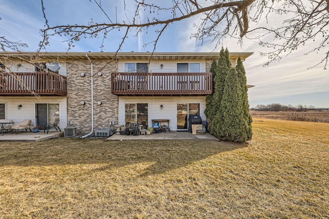 rear view of house with a yard, a patio, brick siding, and central AC