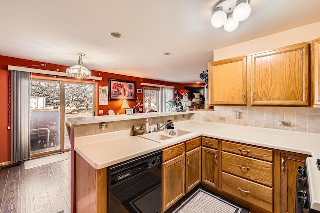 kitchen with a peninsula, a sink, light countertops, dishwasher, and range