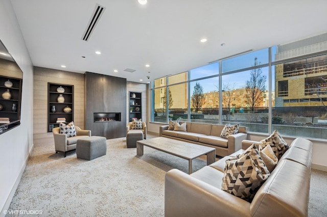 carpeted living area with visible vents, built in shelves, recessed lighting, a large fireplace, and baseboards