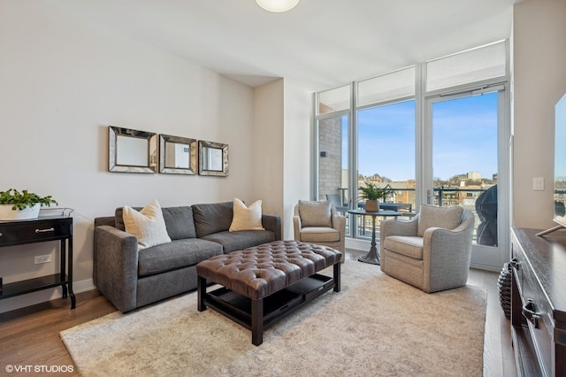 living room featuring floor to ceiling windows, baseboards, and wood finished floors