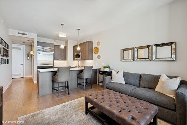 living area with baseboards, visible vents, and light wood finished floors