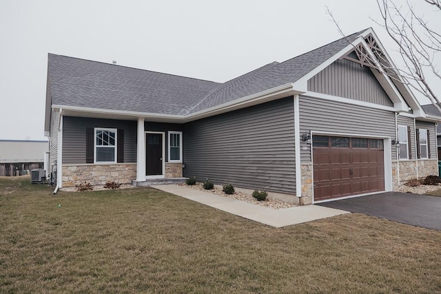 view of front of property featuring a front lawn, aphalt driveway, cooling unit, a garage, and stone siding