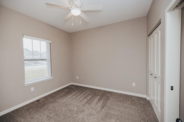 unfurnished bedroom with visible vents, baseboards, ceiling fan, a closet, and dark carpet