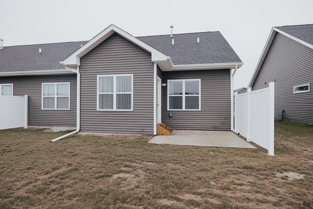 rear view of house featuring a patio, a lawn, roof with shingles, and fence