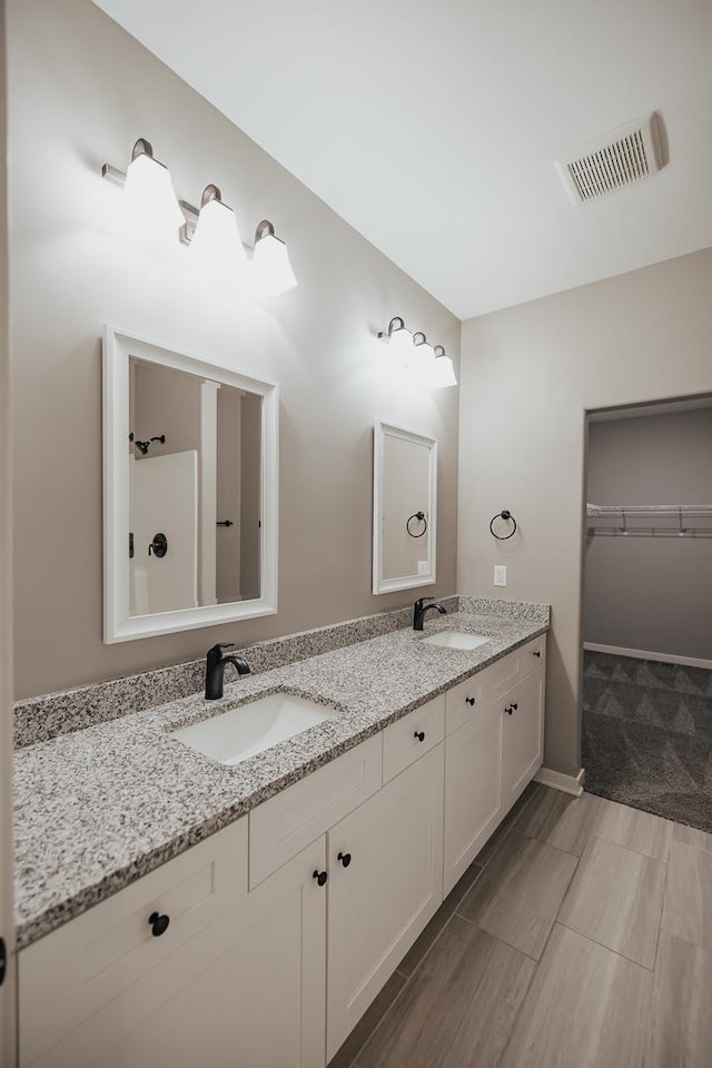 full bath featuring a sink, visible vents, a spacious closet, and double vanity