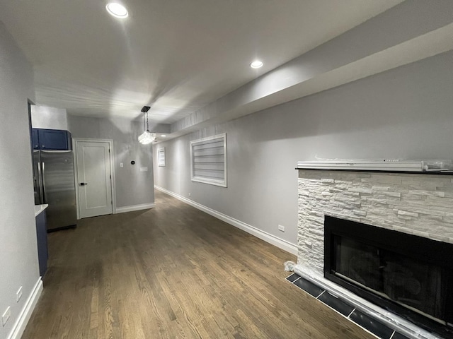 unfurnished living room with a stone fireplace, recessed lighting, baseboards, and dark wood-style flooring