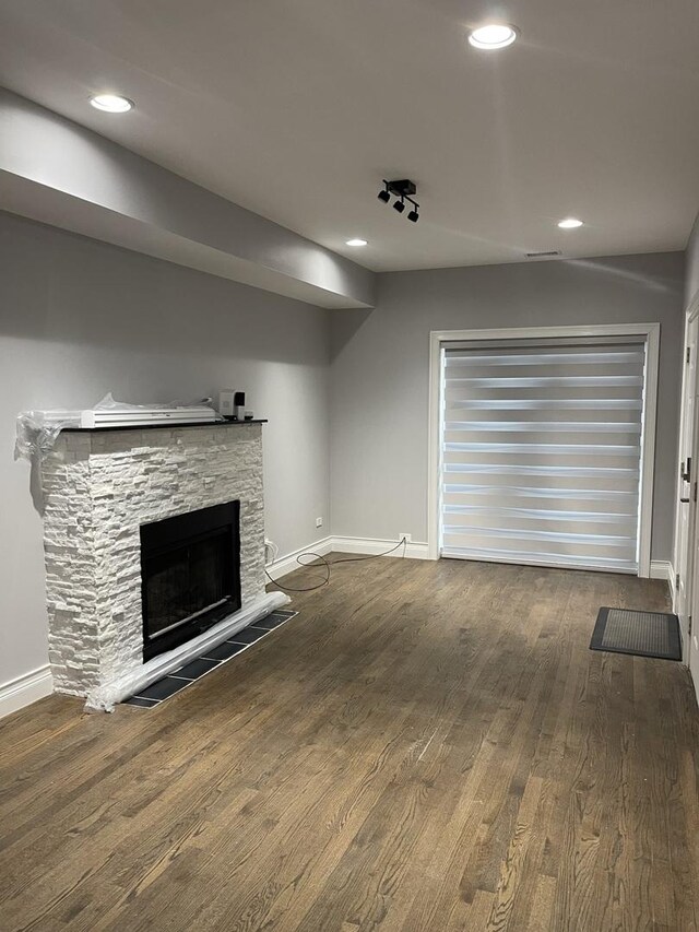 unfurnished living room featuring recessed lighting, baseboards, wood finished floors, and a fireplace