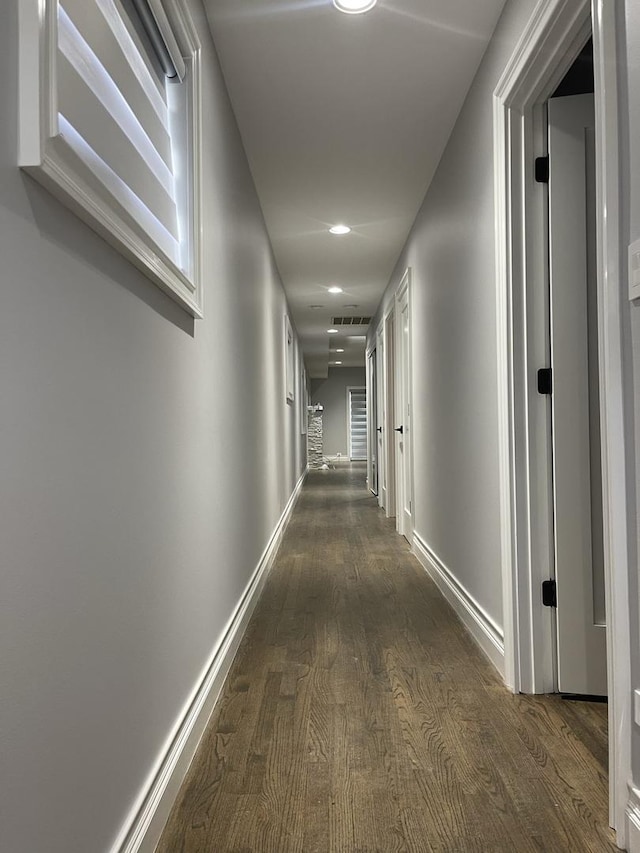 hall featuring dark wood-style floors, visible vents, and baseboards