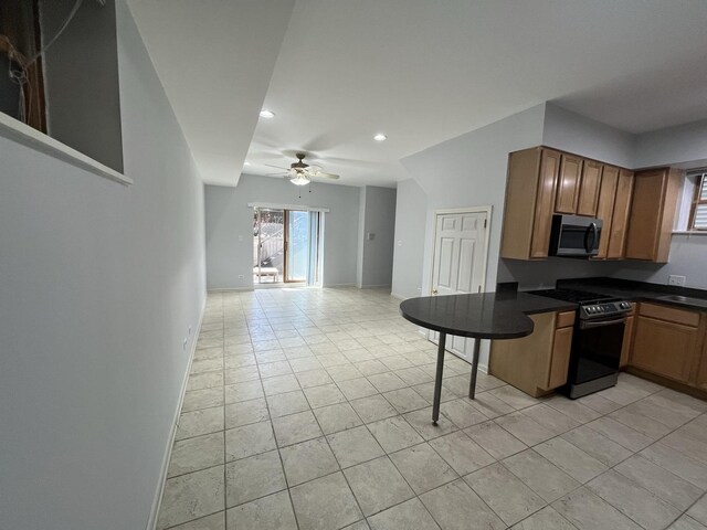 kitchen with a kitchen breakfast bar, dark countertops, open floor plan, appliances with stainless steel finishes, and ceiling fan