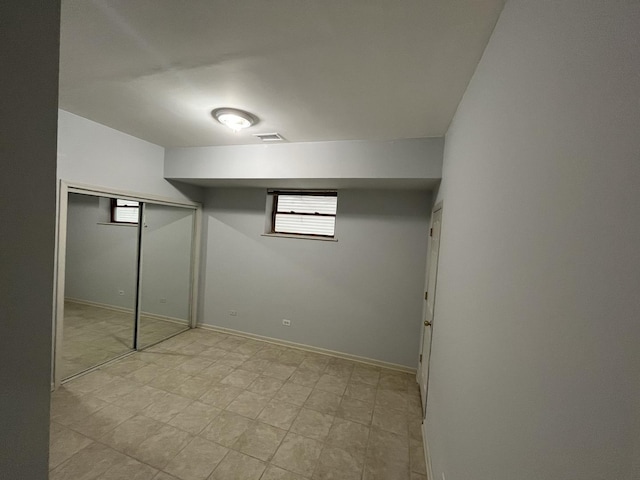 basement with visible vents, light floors, and baseboards