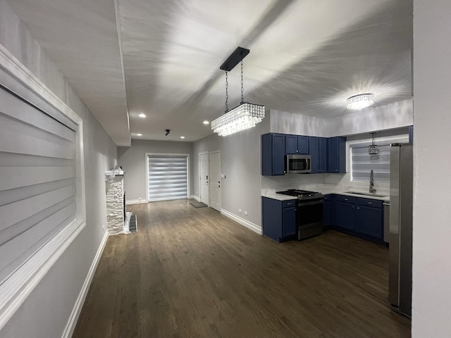 kitchen with dark wood-type flooring, blue cabinetry, a sink, stainless steel appliances, and light countertops