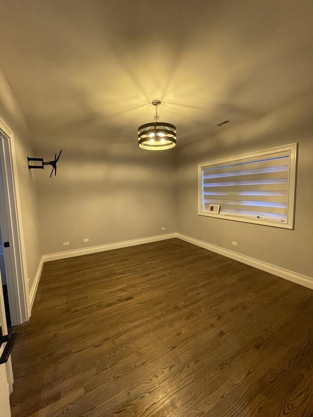 unfurnished room featuring visible vents, dark wood-type flooring, and baseboards