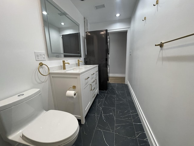 bathroom featuring visible vents, toilet, marble finish floor, a sink, and baseboards