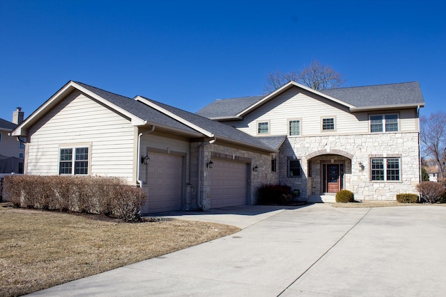 traditional-style house with stone siding, a garage, driveway, and a shingled roof