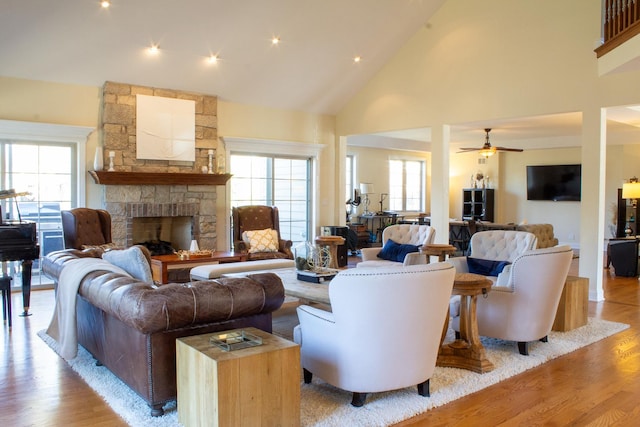 living area with light wood-style flooring, high vaulted ceiling, ceiling fan, and a fireplace