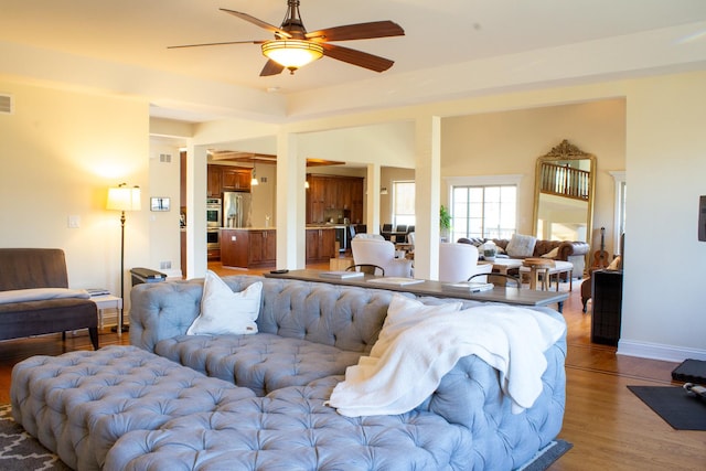 living area with baseboards, ceiling fan, and light wood finished floors