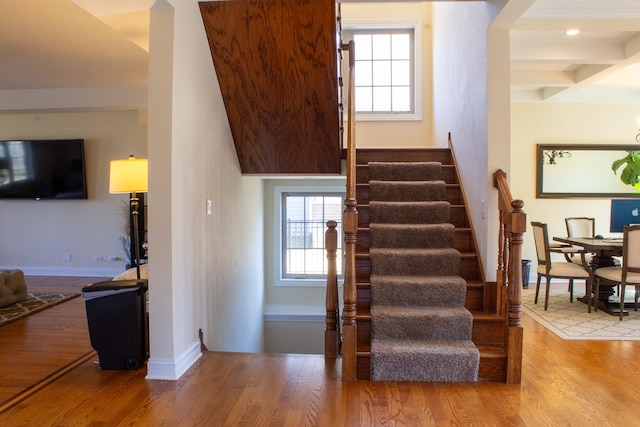 stairway with beamed ceiling, coffered ceiling, baseboards, and wood finished floors