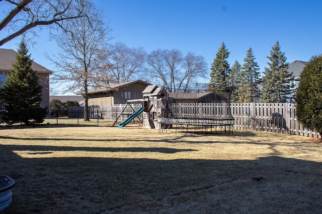 view of yard with a trampoline, a fenced backyard, and playground community