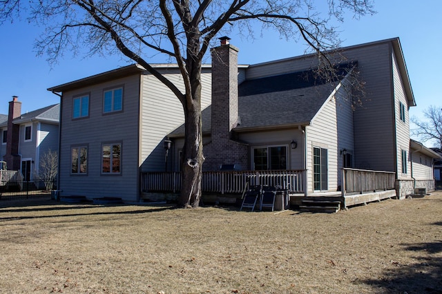 back of house featuring a wooden deck, a yard, a chimney, and fence