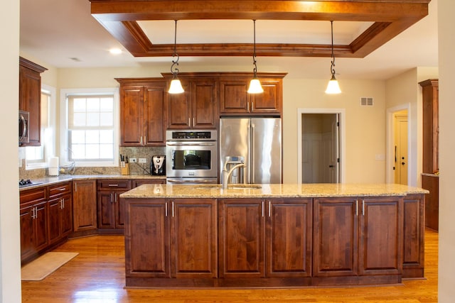 kitchen with a raised ceiling, light wood-style flooring, visible vents, and appliances with stainless steel finishes
