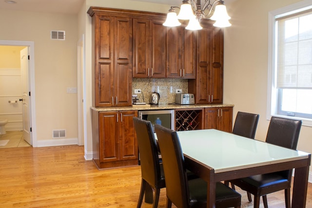 dining space featuring a chandelier, visible vents, light wood-type flooring, and baseboards