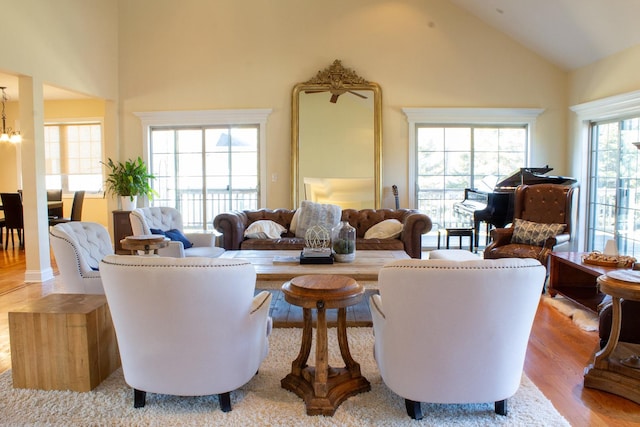living room with high vaulted ceiling, an inviting chandelier, and wood finished floors