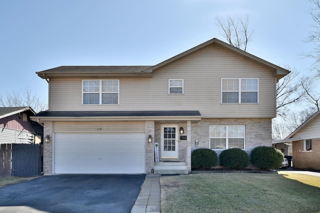 traditional-style house featuring brick siding, fence, a front yard, a garage, and driveway