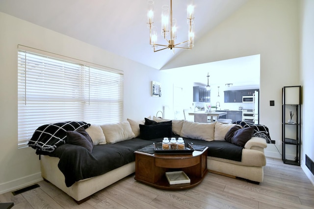 living area featuring light wood-type flooring, visible vents, baseboards, and a notable chandelier