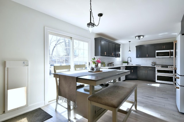 kitchen with double oven range, light countertops, decorative backsplash, light wood-style floors, and hanging light fixtures