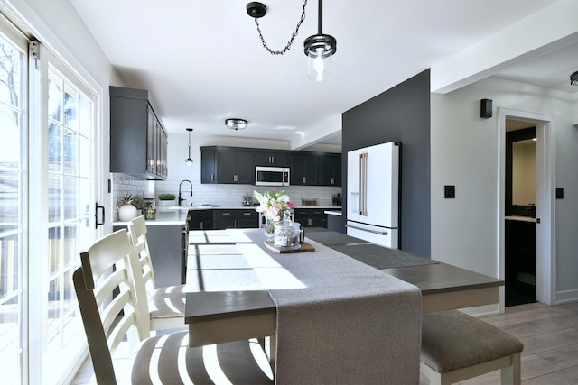 kitchen featuring backsplash, light countertops, light wood-type flooring, white appliances, and a sink