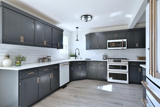 kitchen featuring a sink, double oven range, light countertops, and white dishwasher