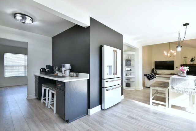 kitchen with baseboards, a chandelier, high end white refrigerator, light wood-style flooring, and hanging light fixtures