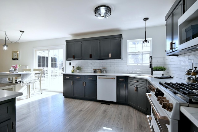 kitchen with white appliances, light wood-style flooring, a healthy amount of sunlight, and pendant lighting