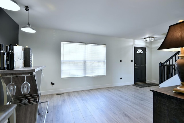 living area with stairway, light wood-type flooring, and baseboards