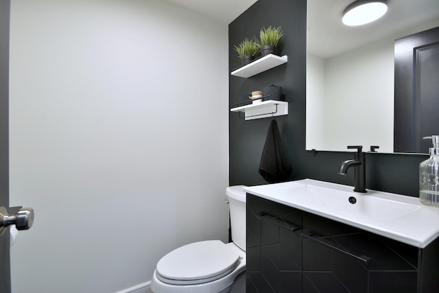 bathroom featuring baseboards, toilet, and vanity