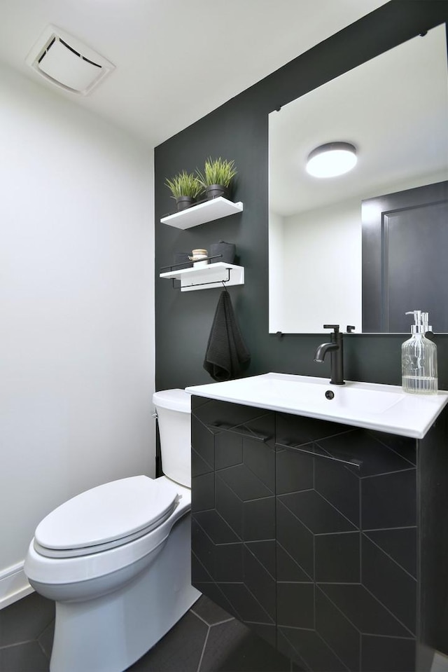 half bath with tile patterned floors, visible vents, toilet, and a sink