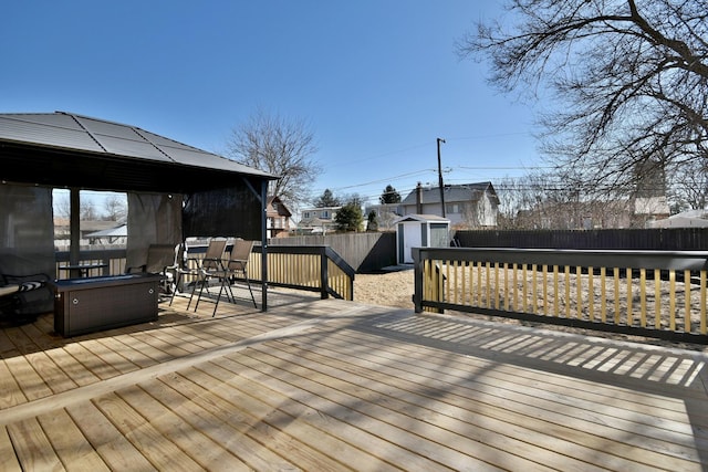 wooden terrace with outdoor dining space, a fenced backyard, an outdoor structure, a gazebo, and a storage unit