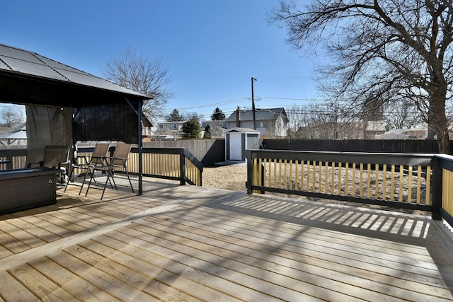 deck with a gazebo, a storage shed, a fenced backyard, an outdoor structure, and outdoor dining space