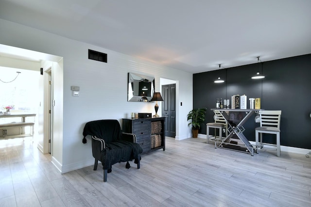 sitting room with light wood finished floors, visible vents, and baseboards