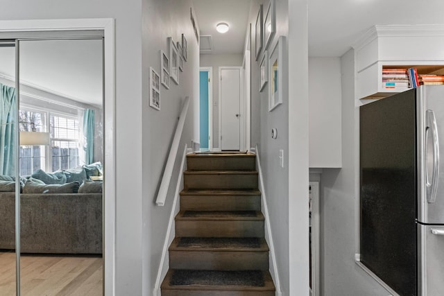 stairway with crown molding, baseboards, and wood finished floors