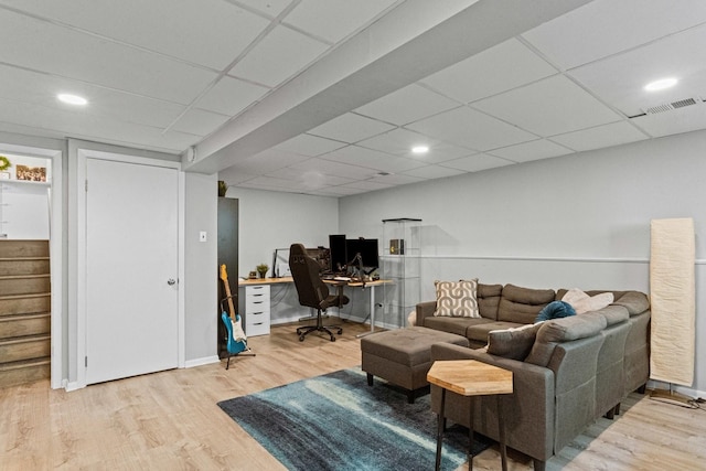 living area featuring visible vents, baseboards, stairway, a drop ceiling, and wood finished floors