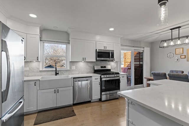 kitchen featuring a sink, light wood-style floors, appliances with stainless steel finishes, white cabinetry, and tasteful backsplash