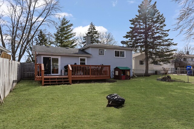 rear view of property with a lawn, a fenced backyard, an outdoor fire pit, a wooden deck, and a chimney