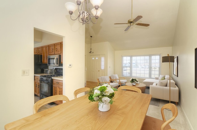 dining room with ceiling fan with notable chandelier, baseboards, and high vaulted ceiling