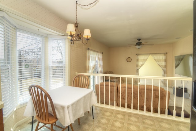 dining space featuring plenty of natural light, ceiling fan with notable chandelier, and wallpapered walls