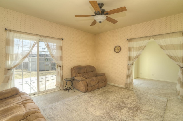 living area with wallpapered walls, a ceiling fan, baseboards, and carpet floors