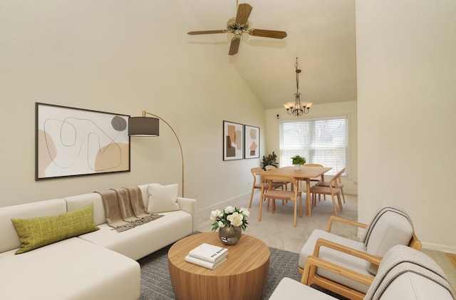 living area with ceiling fan with notable chandelier, light colored carpet, high vaulted ceiling, and baseboards